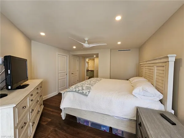 a spacious bedroom with a bed and a flat screen tv