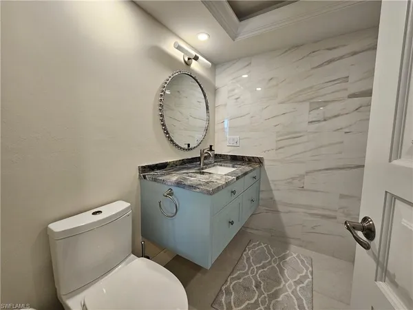 a bathroom with a granite countertop toilet sink and mirror