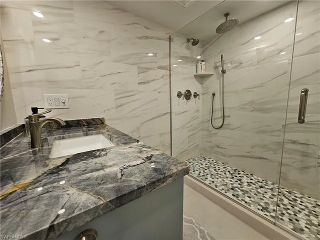 a bathroom with a granite countertop sink a toilet and shower