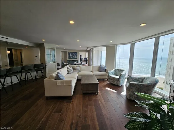 a living room with furniture floor to ceiling window and wooden floor