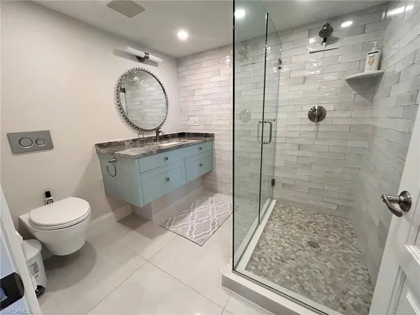 a bathroom with a granite countertop toilet sink mirror and shower