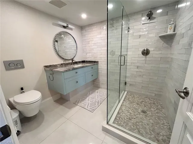 a bathroom with a granite countertop toilet sink mirror and shower