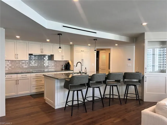 a kitchen with granite countertop a dining table chairs and wooden floor