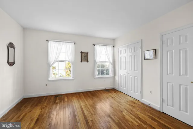 a view of empty room with wooden floor and ceiling fan