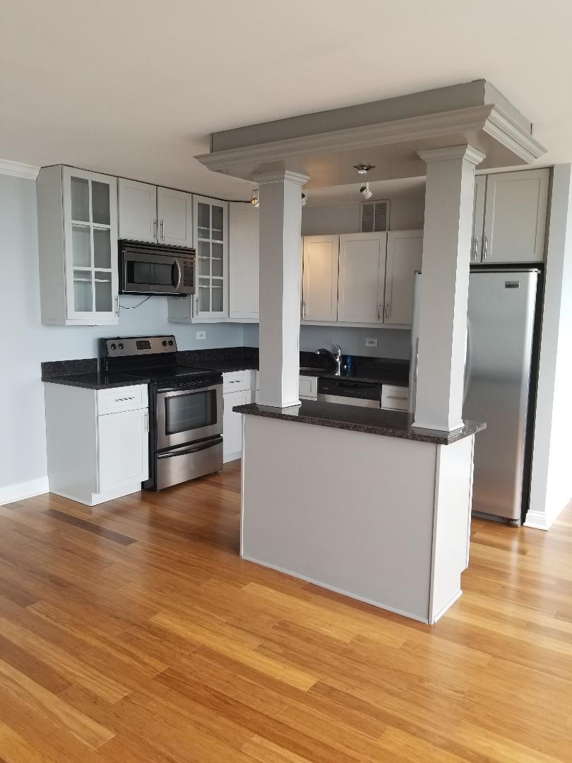 655 West Irving Park Road, Unit 5015 Chicago, IL 60613 - Photo 4 of 25 a large kitchen with stainless steel appliances granite countertop a stove a sink and white cabinets
