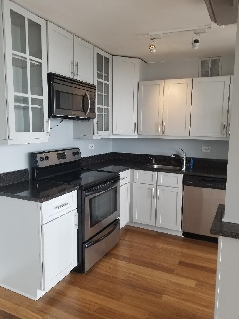 655 West Irving Park Road, Unit 5015 Chicago, IL 60613 - Photo 9 of 25 a kitchen with stainless steel appliances white cabinets and a stove top oven