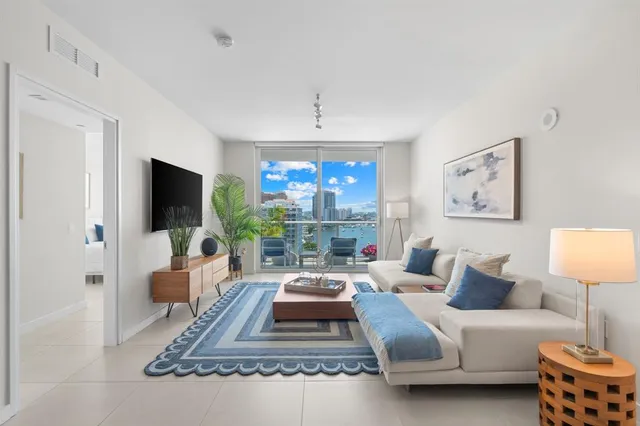 a living room with furniture a flat screen tv and a large window