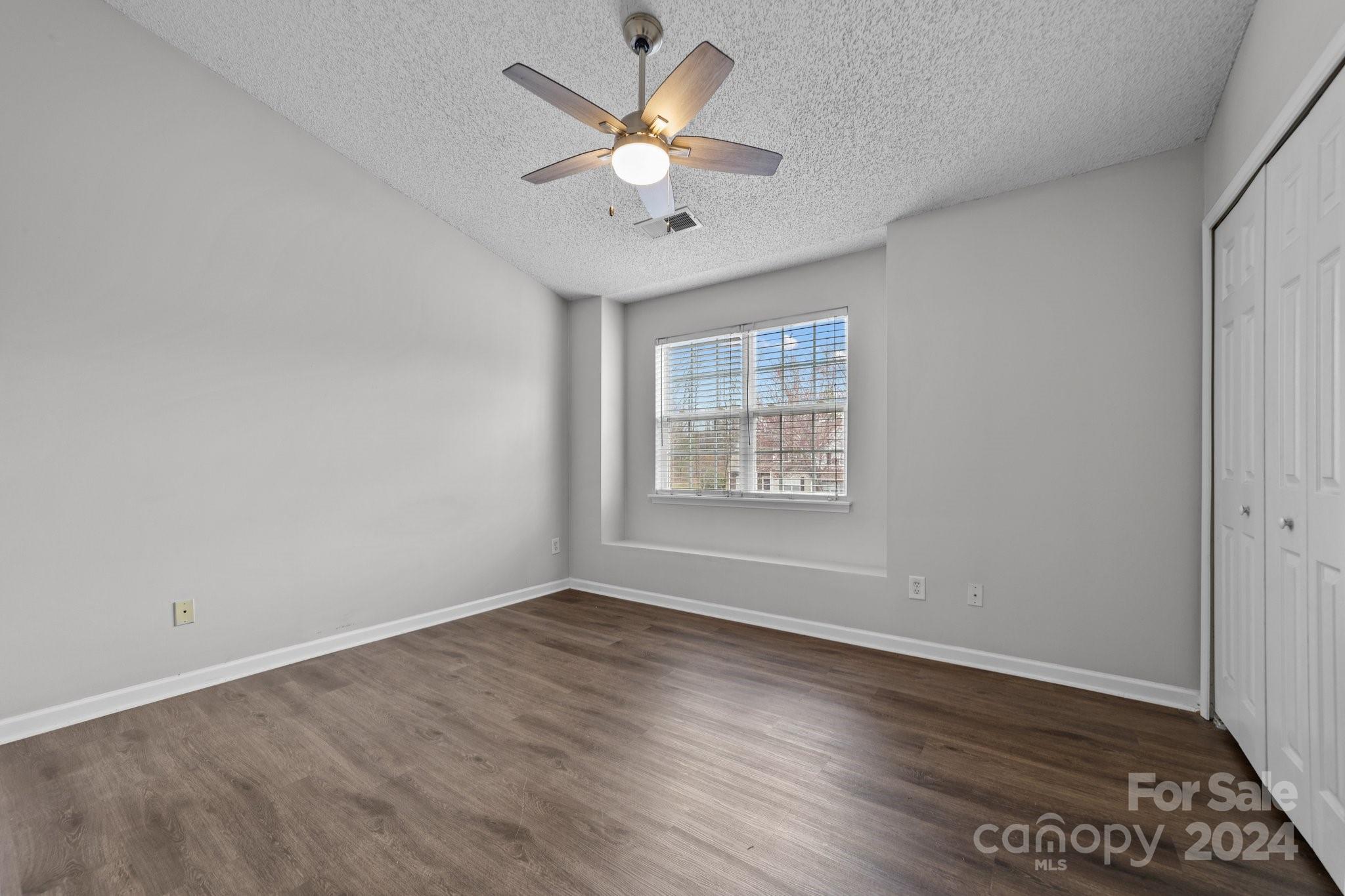 8368 Rudolph Road Charlotte, NC 28216 - Photo 25 of 43 an empty room with wooden floor chandelier fan and windows