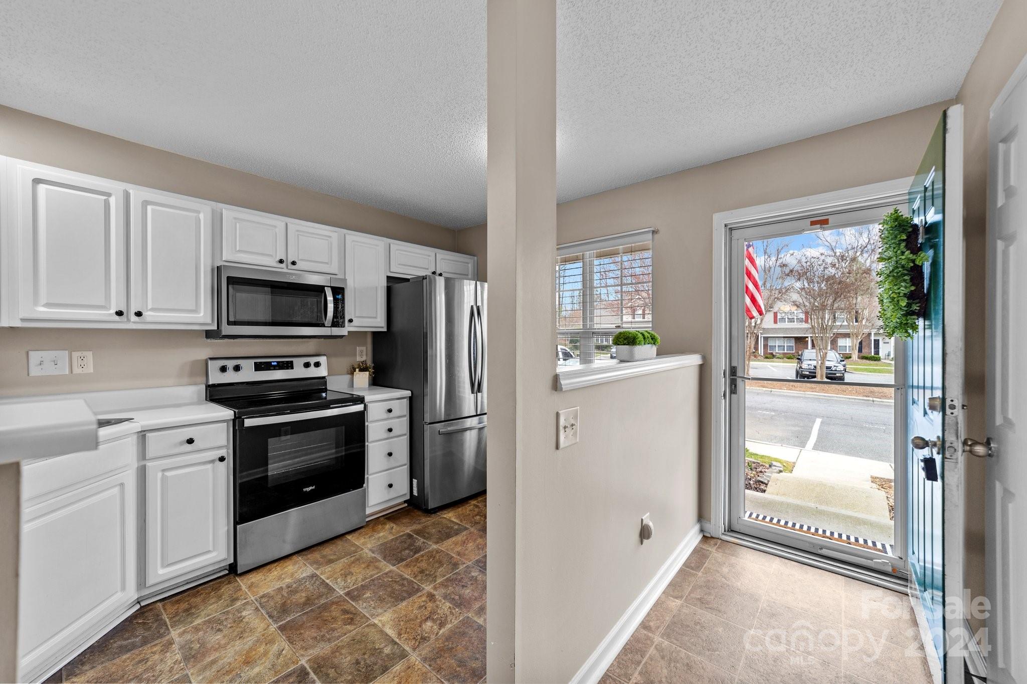 8368 Rudolph Road Charlotte, NC 28216 - Photo 10 of 43 a kitchen with refrigerator a microwave oven cabinets and a counter top space