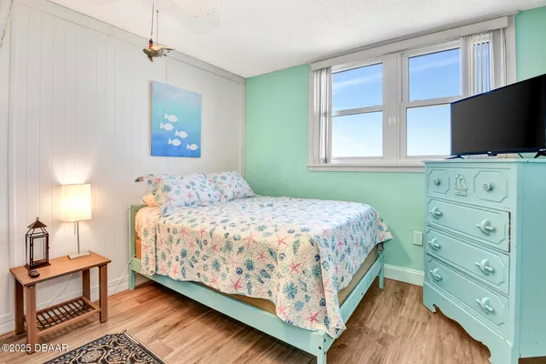 a bedroom with a bed and a flat tv screen on dresser