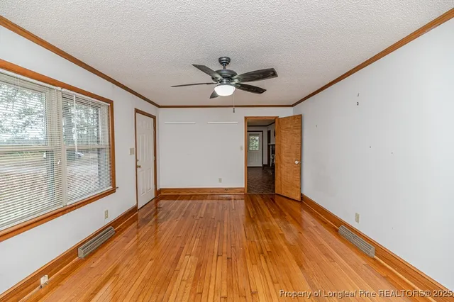a view of empty room with wooden floor and fan