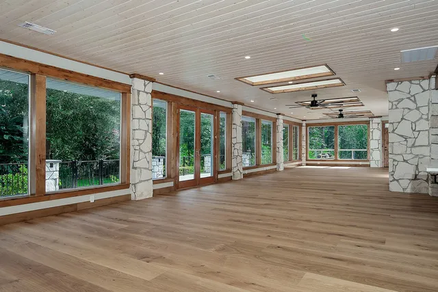 a view of an empty room with wooden floor and a floor to ceiling window