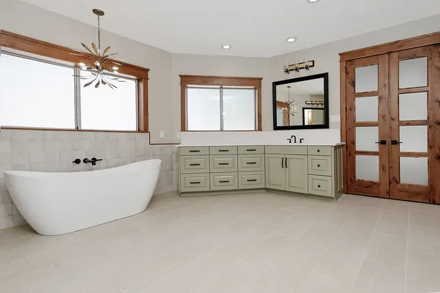 a spacious bathroom with windows bathtub and chandelier