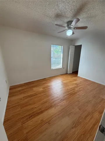 a view of an empty room with window and chandelier fan