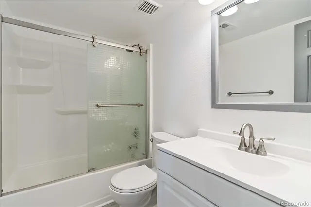 a bathroom with a granite countertop sink toilet and shower