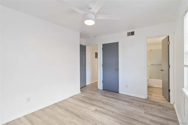 an empty room with wooden floor and ceiling fan