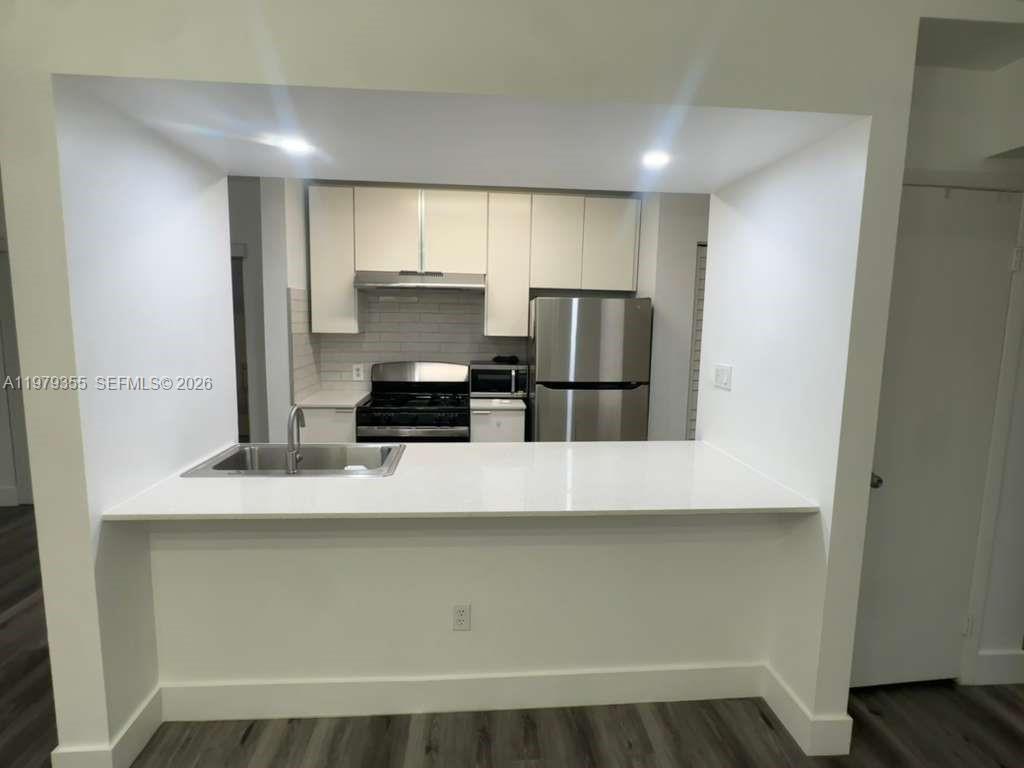 15330 Southwest 106th Terrace, Unit 915 Miami, FL 33196 - Photo 2 of 8 a kitchen with kitchen island a sink appliances and cabinets