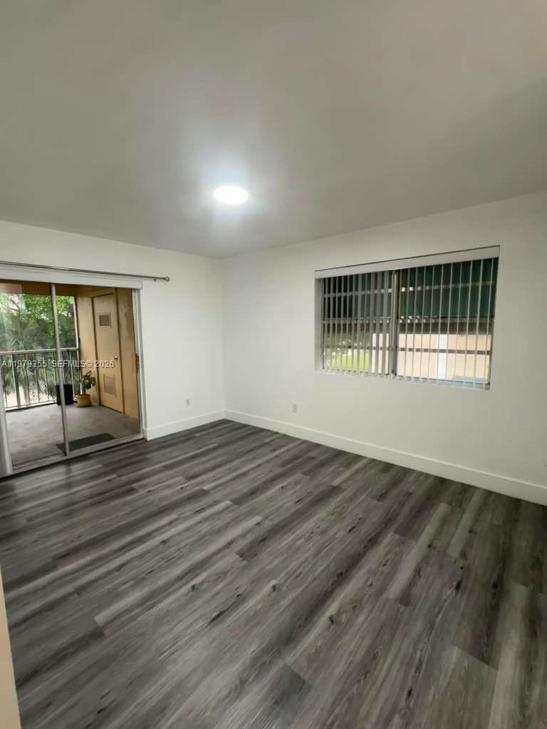 15330 Southwest 106th Terrace, Unit 915 Miami, FL 33196 - Photo 4 of 8 a view of an empty room with wooden floor and a window