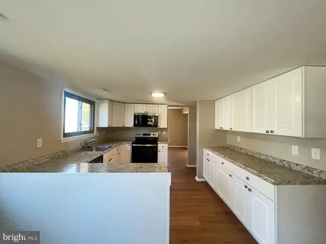 a large kitchen with kitchen island granite countertop a stove top oven a sink a dining table and chairs with wooden floor