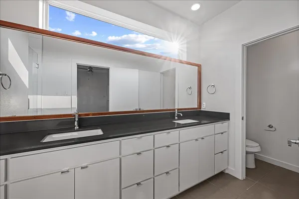 a spacious bathroom with a granite countertop sink a mirror and a shower