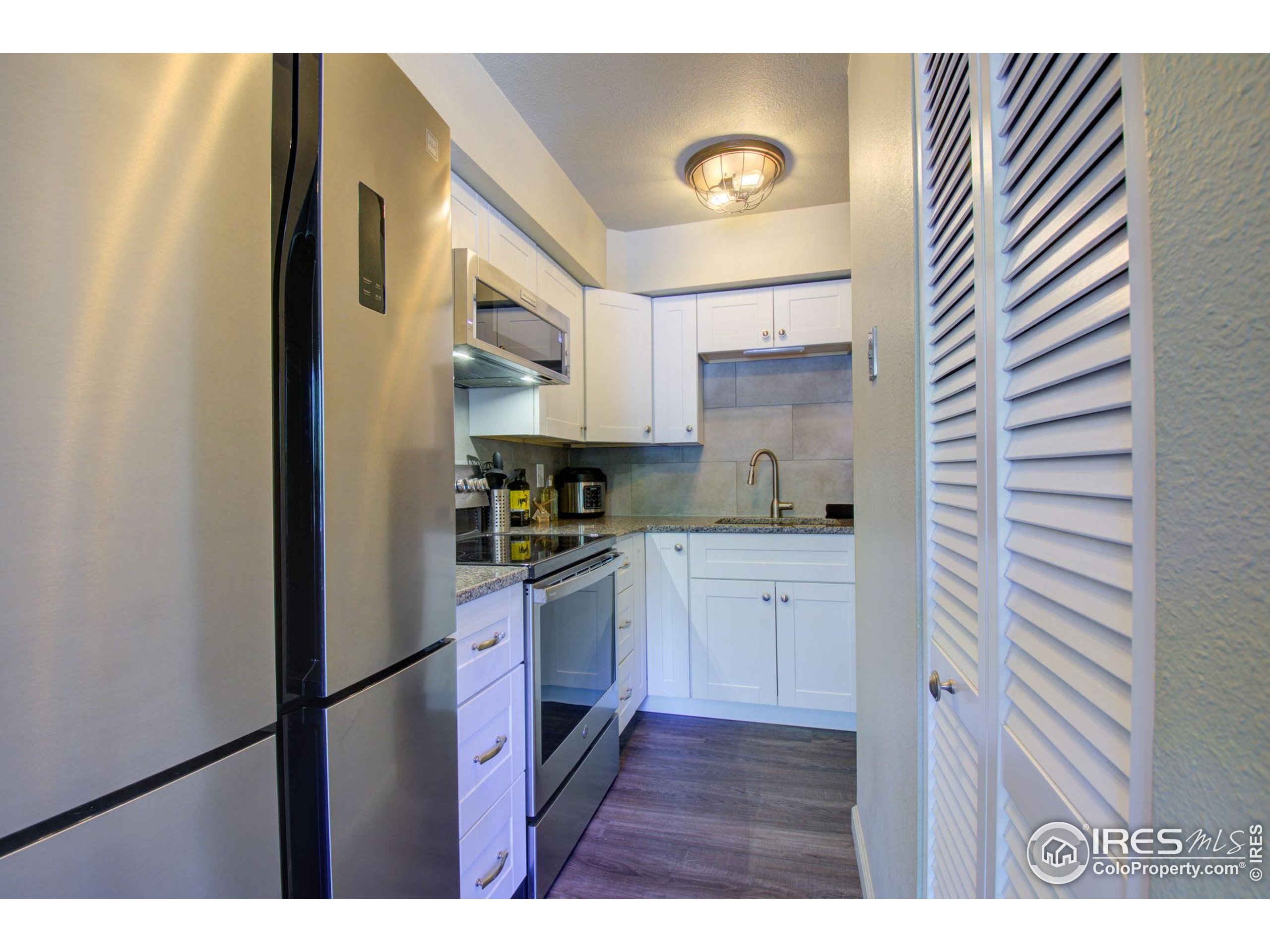 1705 Heatheridge Road, Unit M204 Fort Collins, CO 80526 - Photo 7 of 35 a kitchen with stainless steel appliances granite countertop a refrigerator sink and white cabinets