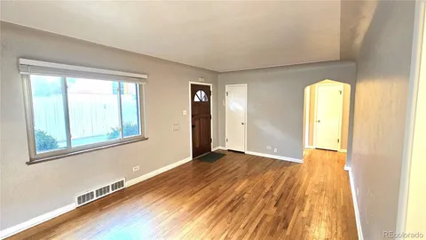 a view of an empty room with wooden floor and a window