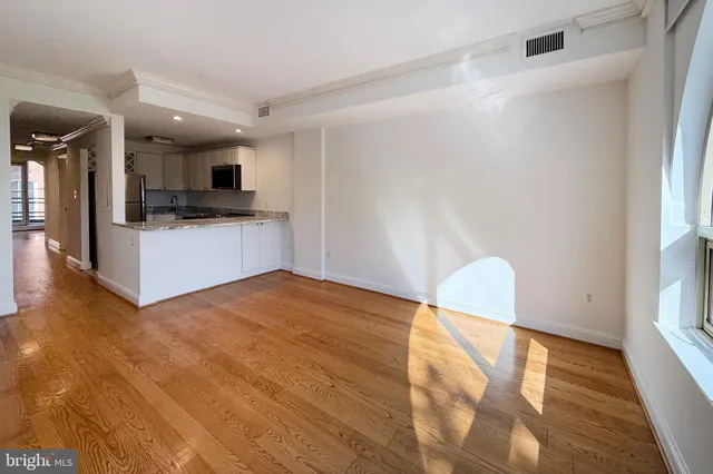 a view of kitchen and empty room with wooden floor