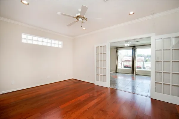 an empty room with wooden floor cabinet and windows