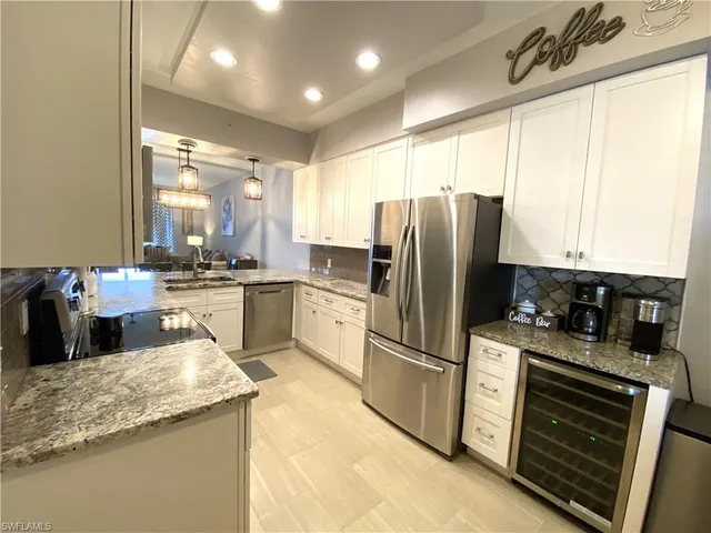 a kitchen with a sink a counter top space stainless steel appliances cabinets and a large window