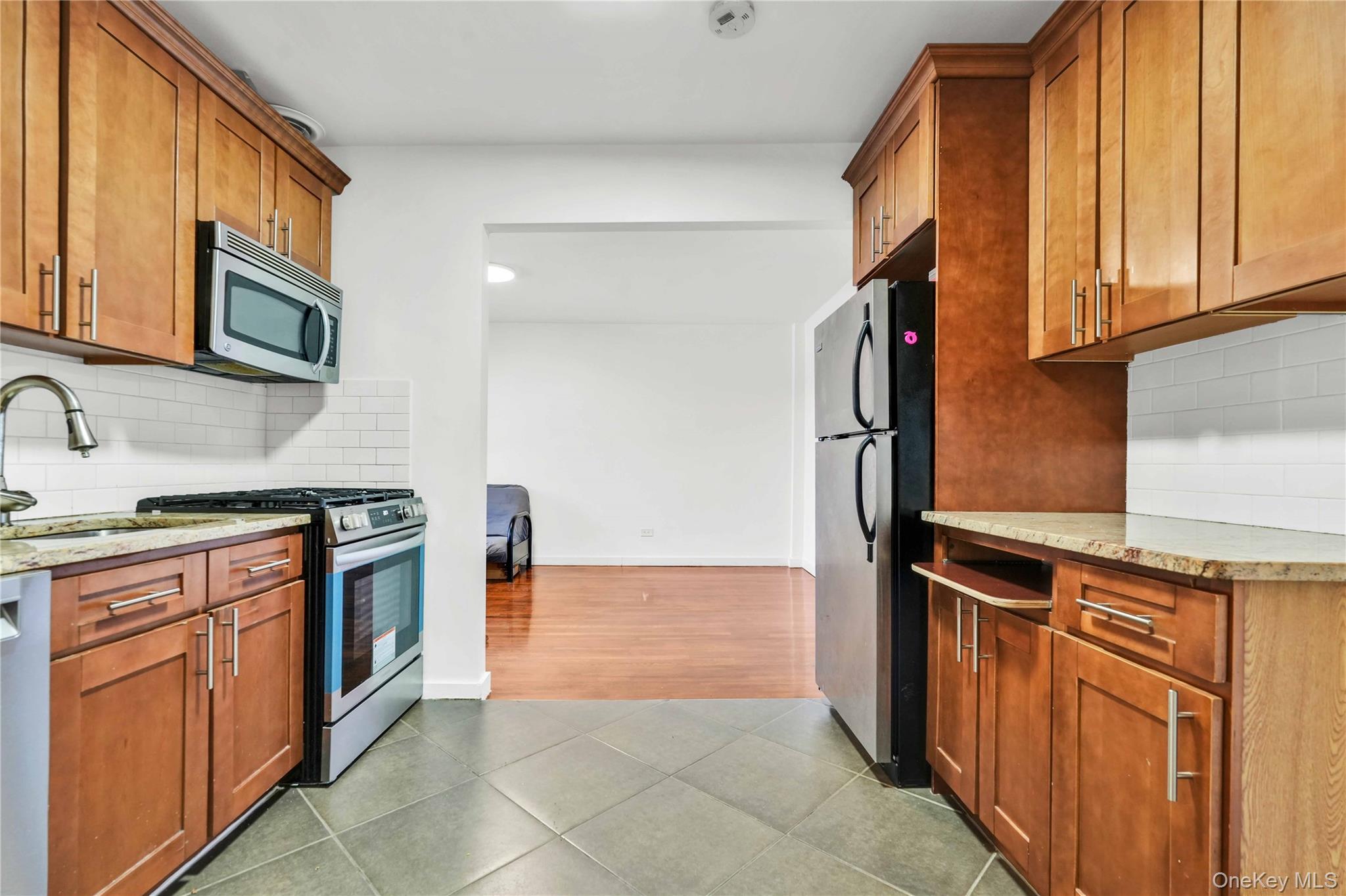 150-29 72nd Road, Unit 4H Queens, NY 11367 - Photo 8 of 16 a kitchen with stainless steel appliances granite countertop a refrigerator and a stove top oven