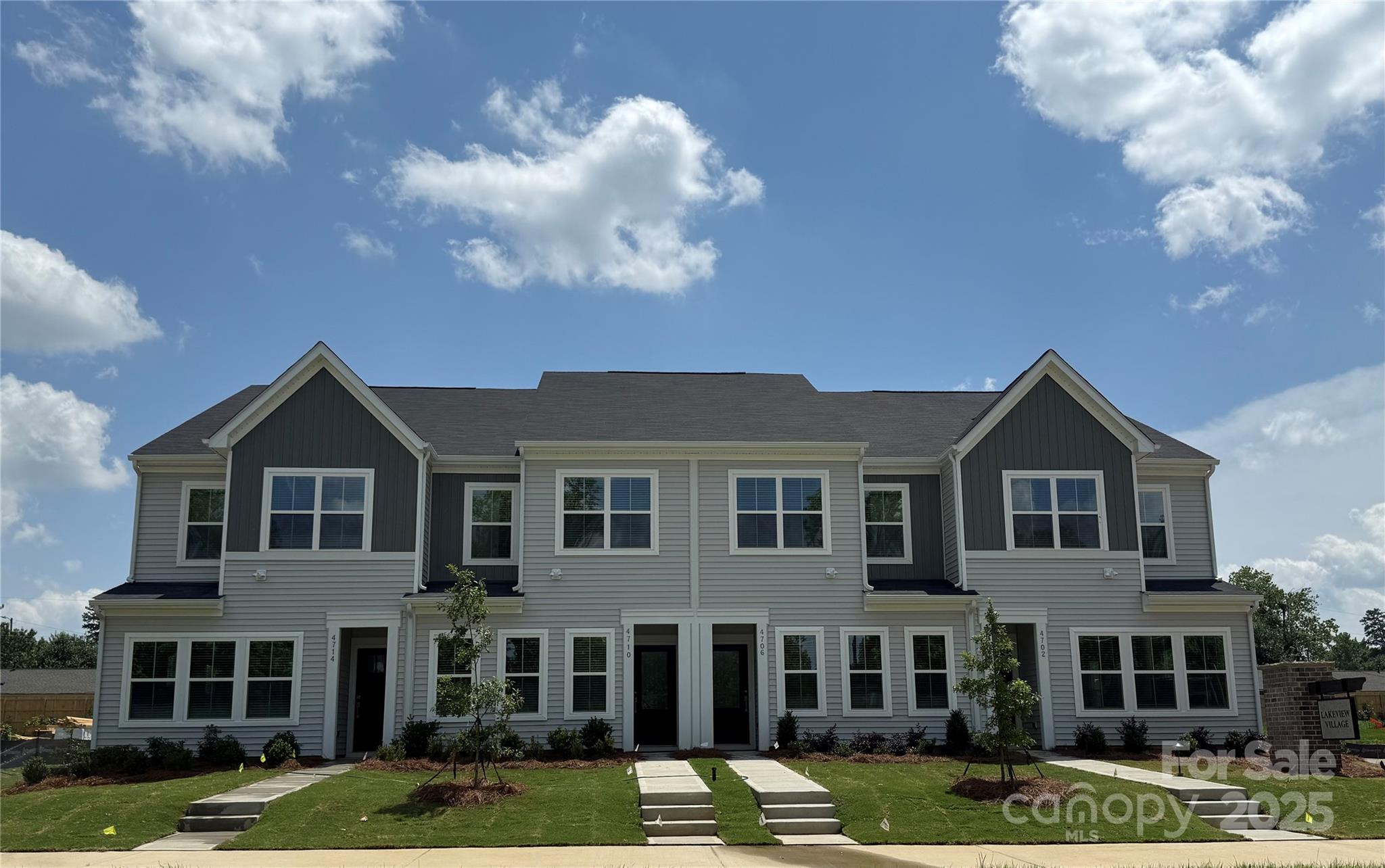 a front view of a residential apartment building with yard and parking around