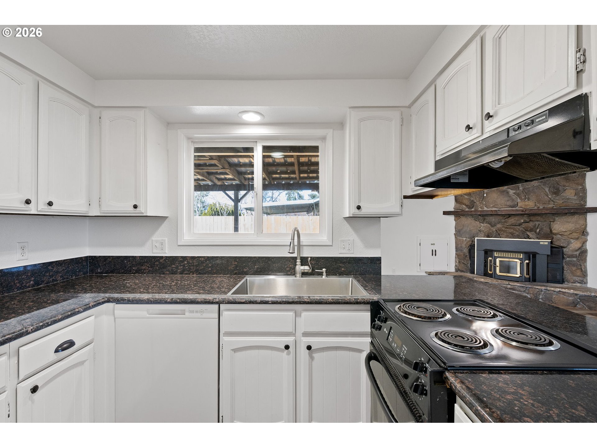 422 South 49th Place Springfield, OR 97478 - Photo 9 of 32 a kitchen with granite countertop a stove sink and cabinets