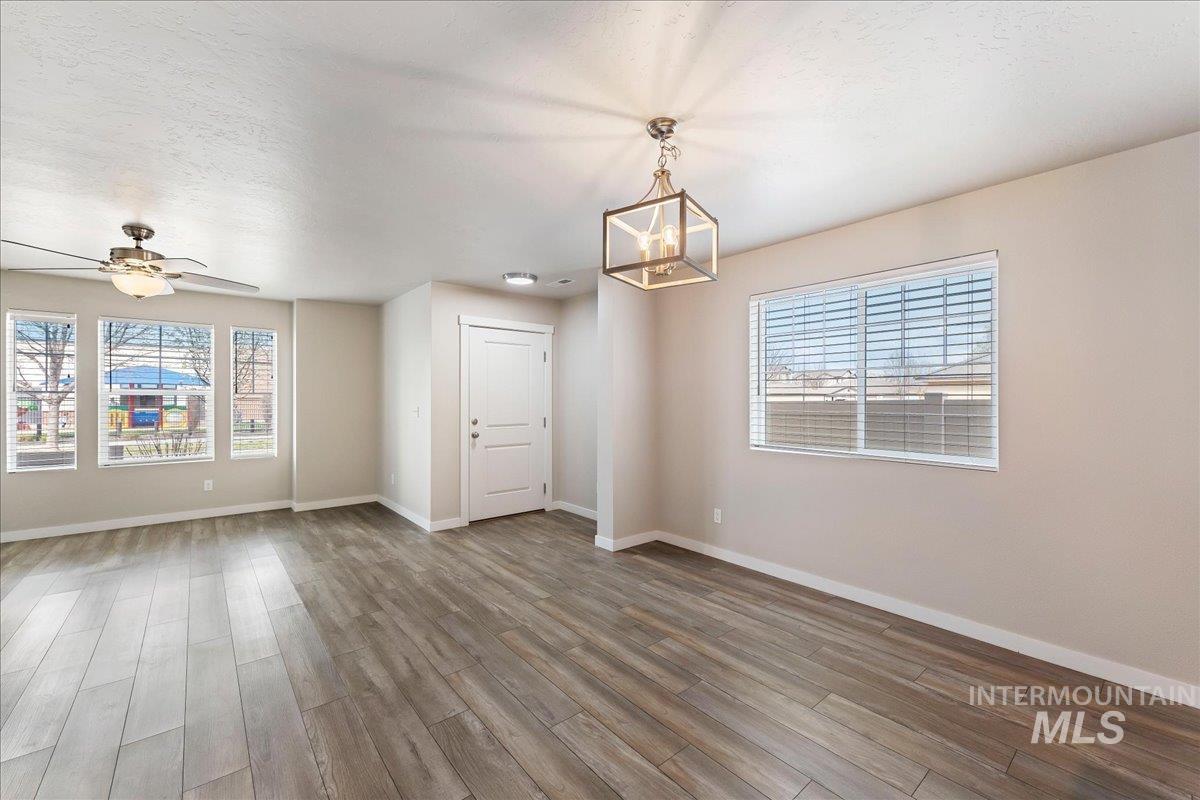 2517 East Goldstone Street Meridian, ID 83642 - Photo 7 of 22 Empty room featuring wood finished floors, ceiling fan, hanging lights, and a textured ceiling