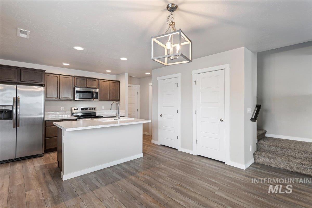 2517 East Goldstone Street Meridian, ID 83642 - Photo 8 of 22 Kitchen with stainless steel appliances, dark wood finish cabinets, suspended lighting, an island with sink, and dark wood-style flooring