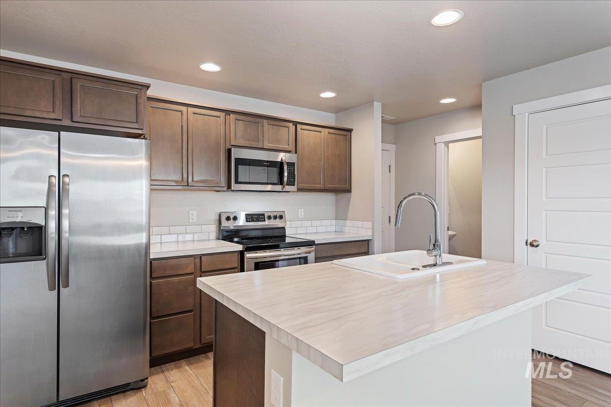 2517 East Goldstone Street Meridian, ID 83642 - Photo 10 of 22 Kitchen featuring stainless steel appliances, light countertops, an island with sink, recessed lighting, and light wood finished floors