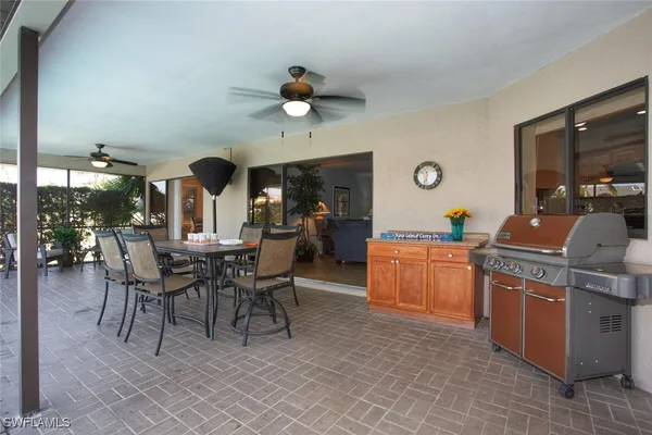 a dining hall with stainless steel appliances kitchen island granite countertop a table and chairs in it