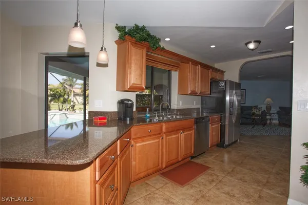 a kitchen with stainless steel appliances granite countertop a sink a stove and a refrigerator