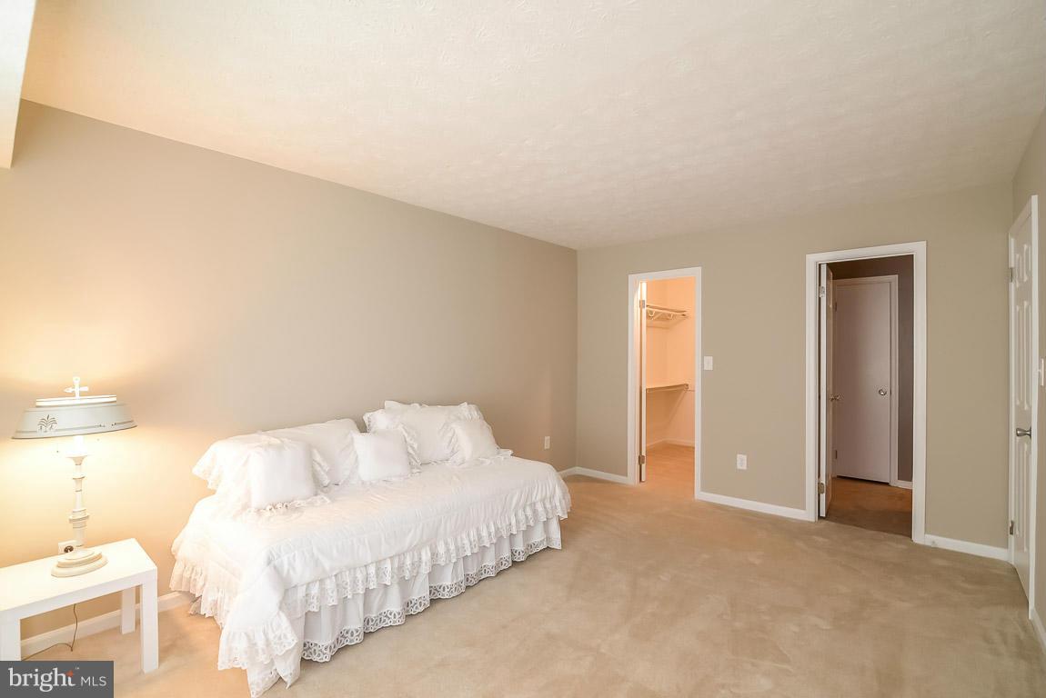 2253 Hunter's Run Drive, Unit 2253 Reston, VA 20191 - Photo 16 of 25 a spacious bedroom with a bed and a lamp