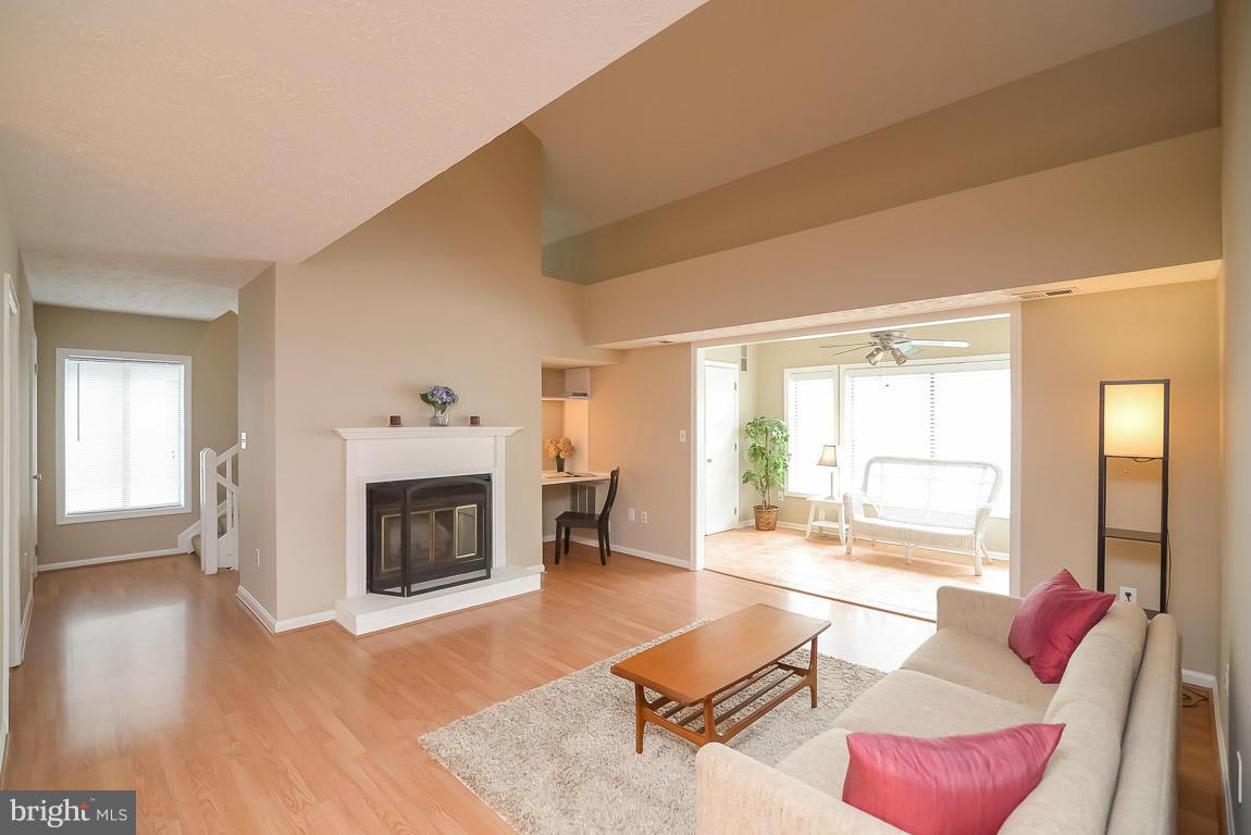 2253 Hunter's Run Drive, Unit 2253 Reston, VA 20191 - Photo 3 of 25 a living room with furniture a fireplace and a floor to ceiling window