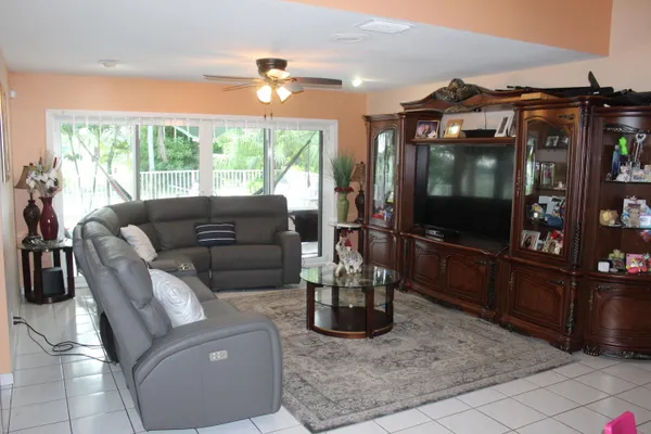 a living room with furniture a flat screen tv and floor to ceiling window