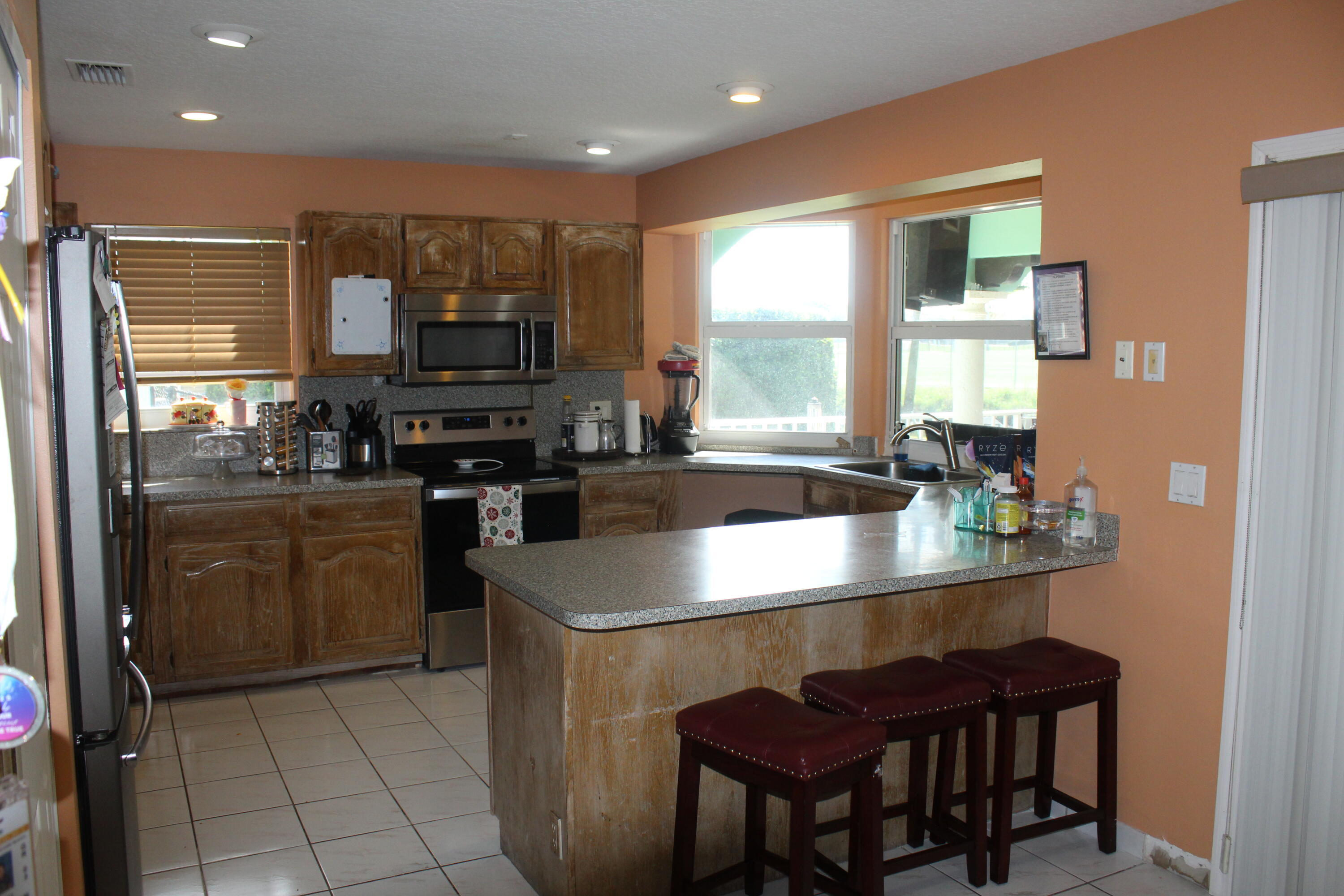 13847 Geranium Place Wellington, FL 33414 - Photo 19 of 50 a kitchen with a stove a sink a microwave a dining table and chairs