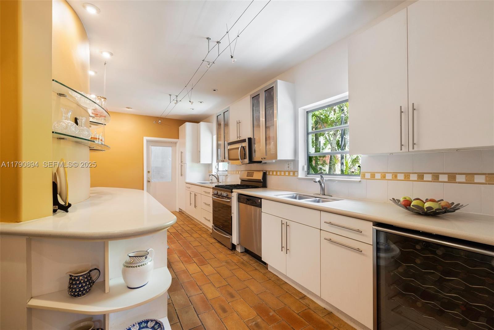 5215 Pine Tree Drive Miami Beach, FL 33140 - Photo 17 of 28 a kitchen with stainless steel appliances a sink a stove a refrigerator cabinets and living room view