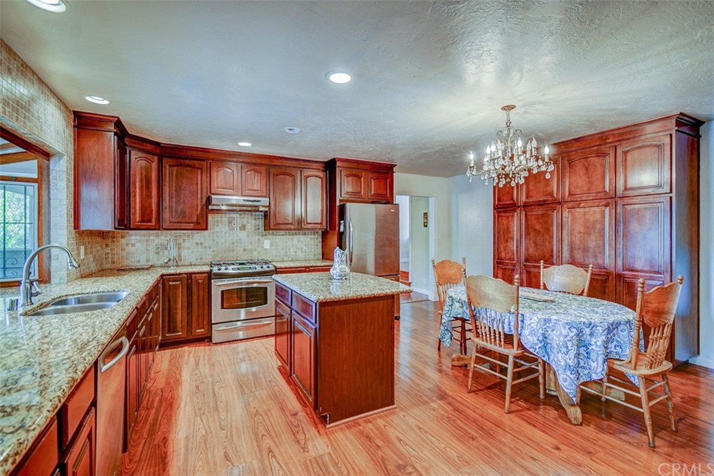 a kitchen that has a table chairs in it wooden floors and a granite counter top