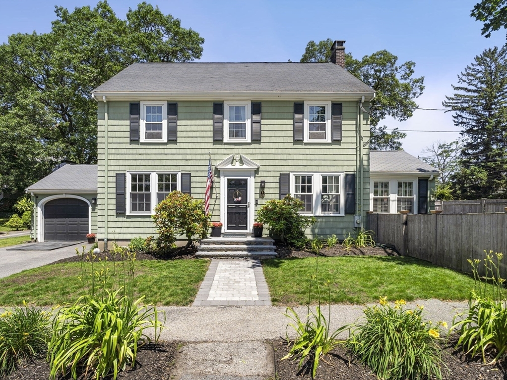 a front view of a house with a yard and potted plants