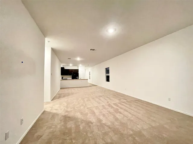 a view of empty room with kitchen