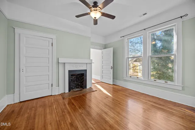 a view of empty room with wooden floor and fireplace