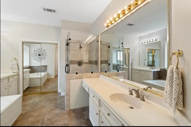 a bathroom with a bathtub a double vanity sink and a window