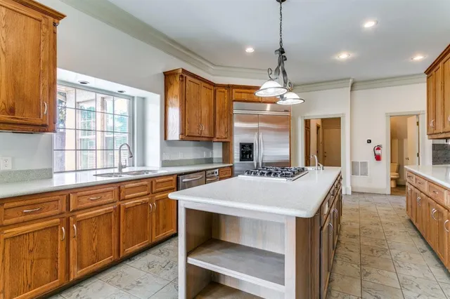 a large white kitchen with a large island oven a sink dishwasher and a fireplace with wooden floor