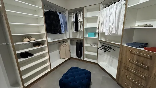 a view of walk in closet with clothes and shoes