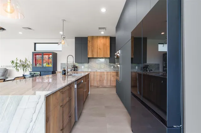 a large kitchen with stainless steel appliances kitchen island granite countertop a large counter top a sink and a refrigerator